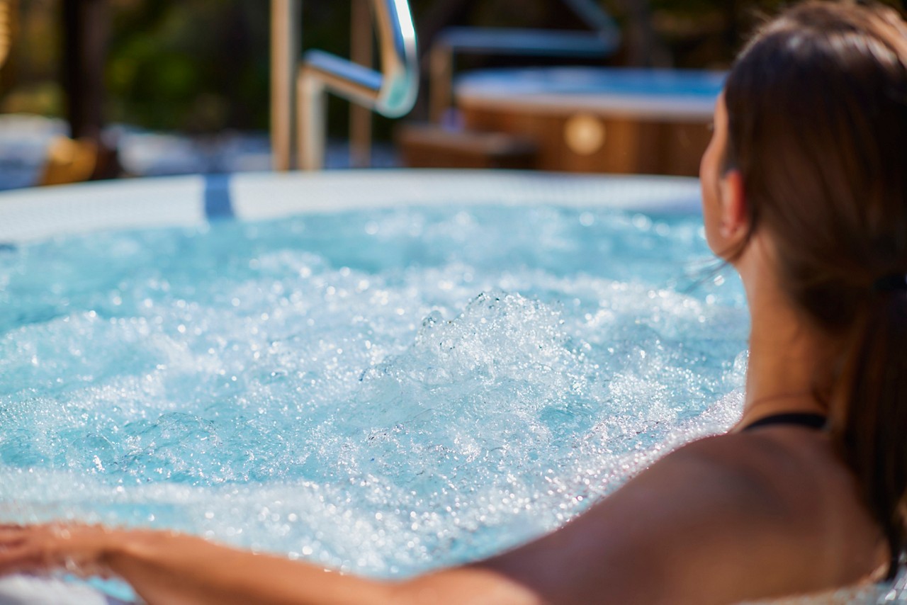 Woman soaking in a bubbling outdoor hot tub.